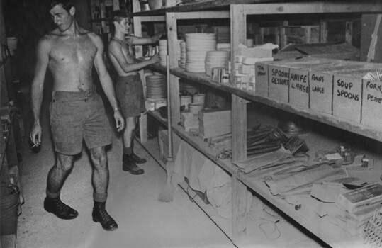 A photograph of Store Assistants in the Quartermasters Store at 1st Australian Field Hospital fill requisitions for mess ware. 