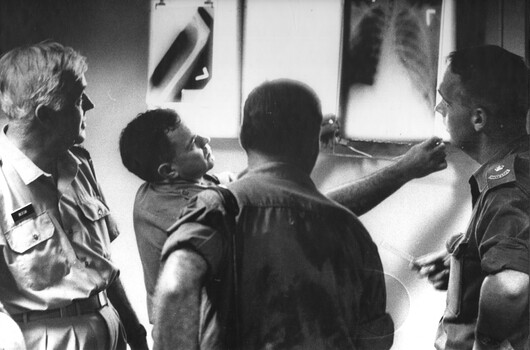 A photograph of RAAF surgeon Wing Commander Alan Beech assisted by triage three medicale officers at the 1st Australian Field Hospital.