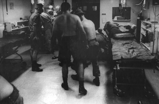 A photograph at the 1st Australian Field Hospital, Vung Tau, South Vietnam, while one triage team in triage team works on a wounded Digger. 