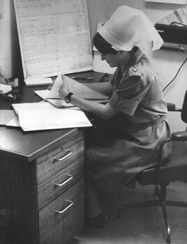 A photograph at 1st Australian Field Hospital, Sister Lt Ann Wright catches up on paperwork in the Sisters Station. 