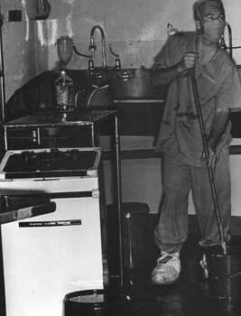 A photograph of a Medic at 1st Australian Field Hospital, Vung Tau, cleans the operating theatre following surgery. 