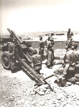 A photograph of Gunners of 161 Battery Royal New Zealand Artillery attached to 1st Australian Field Regiment prepare their gun in parade ground. 