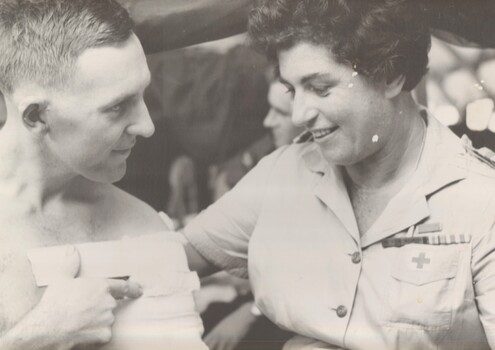 A photograph taken at Vung Tau of Bandsman/Stretcher Bearer Pte Graeme Davis, 6 RAR talking to Australian Red Cross worker Miss Hilda Zimmer.