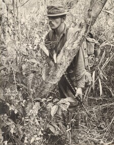 A black and white photograph of a Digger moves through thick jungle during a search and destroy mission.