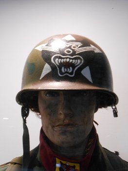 A metal khaki helmet and on the front is a black & white insignia painted in the shape of a panther. 