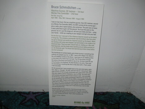 Rectangular white nformation board with black text and green Behind the Wire logo in bottom right corner.