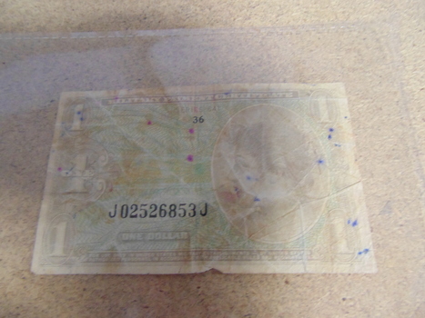 Pale military payment certificate the value of one dollar with reference number J02526853J in black ink at the bottom.  