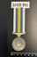 Circular silver service medal on white, blue and yellow striped ribbon. Front show a map of Korea inside concentric circles.