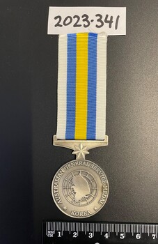 Circular silver service medal on white, blue and yellow striped ribbon. Front show a map of Korea inside concentric circles.