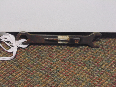 Rusty metal tool for undoing nut and bolts, open at one end and closed at the other.