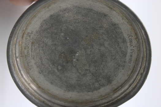 Bottom of pewter mug with makers stamp in metal.