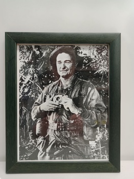 Black and white image of soldier in army fatigues holding a camera.