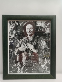 Black and white image of soldier in army fatigues holding a camera.