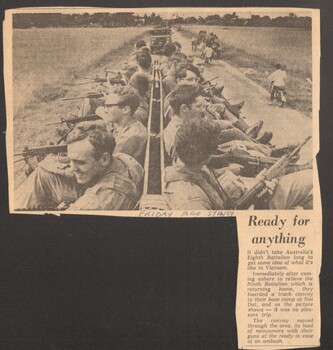 Newspaper article from titled "ready for anything" with an image of a armed troops and the locals going about their daily business.    