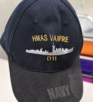 A navy blue cotton cap with black nubuk embossed navy insignia