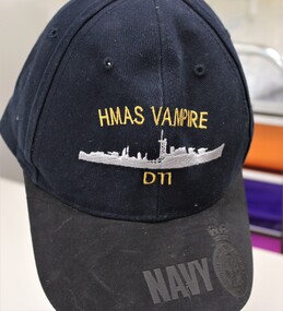 A navy blue cotton cap with black nubuk embossed navy insignia
