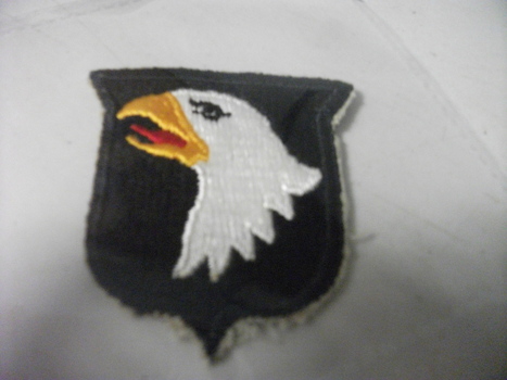 A shield shape black patch with an embroidered eagle. 