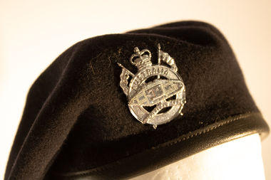 A dark blue beret worn by Royal Australian Signals Corp with hat badge in the centre.