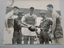 Black and white photo of three Australian soldiers and two vietnamese Soliders with an aussie rules football. 