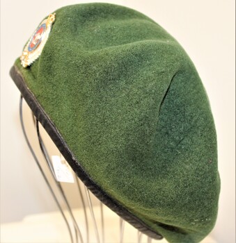 Green beret with a New Zealand Infantry Badge attached.