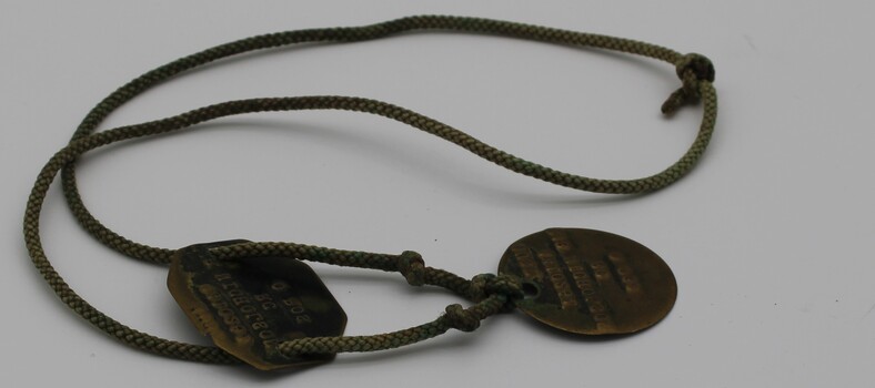 metal discs on cord identifying serviceman TJB Nicholson.
