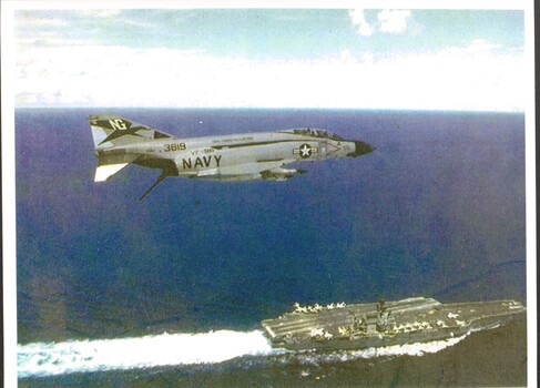 A coloured photograph of a United States Navy air craft carrier loaded being escorted by an air crafter carrier Phantom.  #3819.  