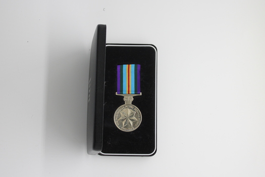 A miniature Australian Active Service medal presented in a black box with the ribbons and bars.