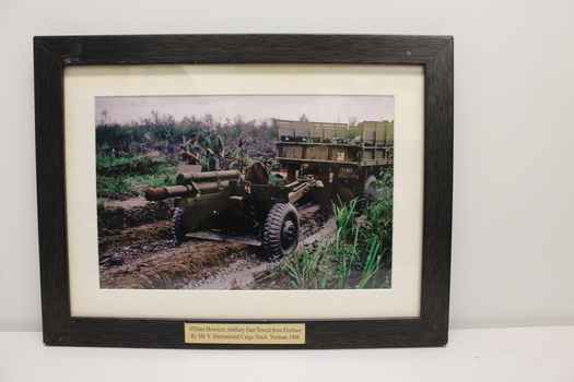 Coloured image of a truck towing a artillary gun, 105mm Howitzer.