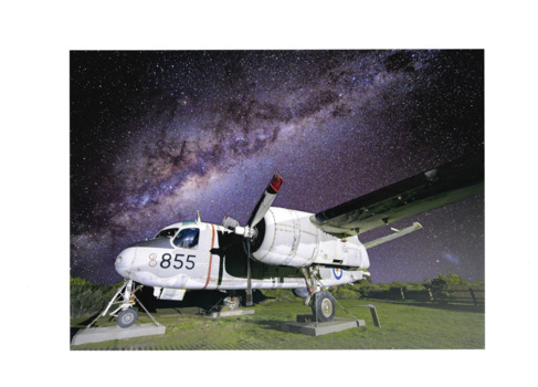 Image of pale grey airplane bearing number 855 set against night sky.