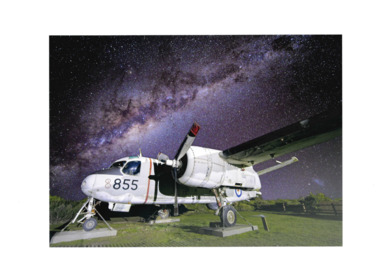 Image of pale grey airplane bearing number 855 set against night sky.