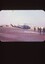 Helicopter in the back ground with four soldiers walking away 