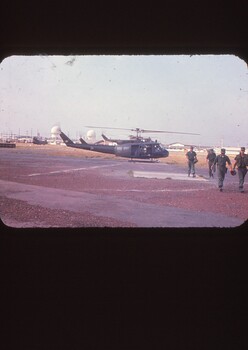 Helicopter in the back ground with four soldiers walking away 
