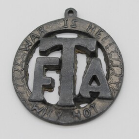 Round Medallion with large FTA in middle, circled by inscription' War is Hell' at top/ 'Why Not' at bottom.