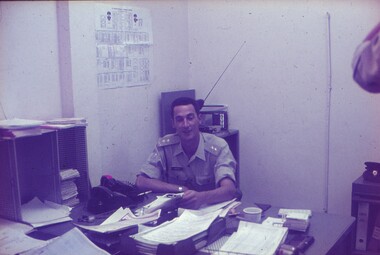 Lt Ray Harvey at desk full of papers.