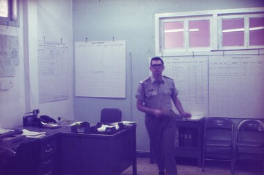 Lt Steve Phillips walking in office with walls covered in charts.