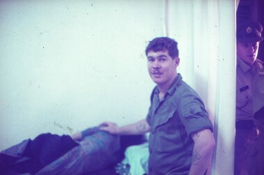 Cpl Egan with hand on local laying on a bed.
