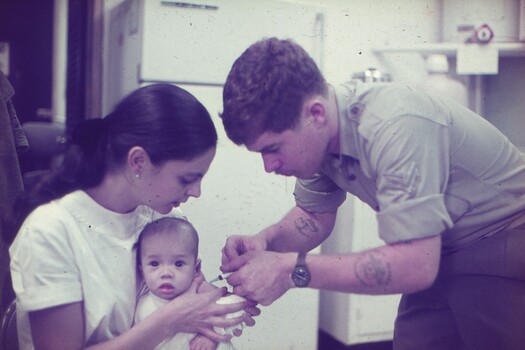 Cpl Egan administering a needle to a baby.