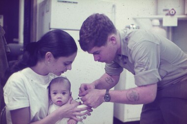 Cpl Egan administering a needle to a baby.