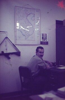 Cpl Sims at his desk, turning to look at the camera for photo.