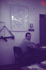 Cpl Sims at his desk, turning to look at the camera for photo.