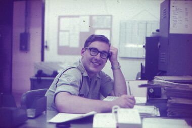 Cpl Sims smiling at the camera at his desk