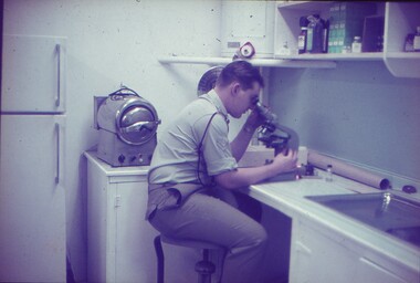 Cpl Sims looking into a microscope.