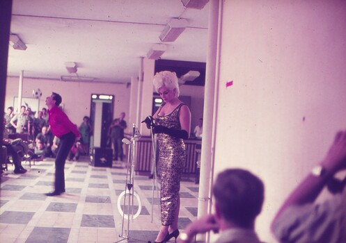 Male entertainer performing with ball, while assistant prepares swords for show.