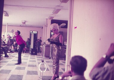 Male entertainer performing with ball, while assistant prepares swords for show.