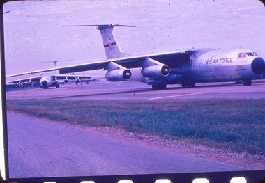 Three C-141 starlifter military aircraft lined up on runway.