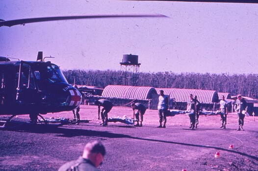 Helicopter in foreground with soldiers carrying stretches to it, at a medical hospital.