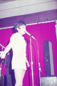 Female entertainer in white dress, performing at the microphone.
