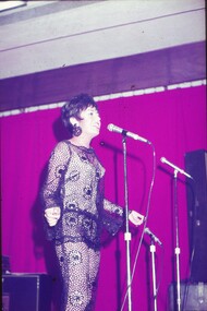 Female entertainer in black lace dress performing at microphone.