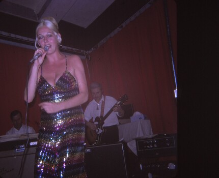 Female entertainer singing with band in background.