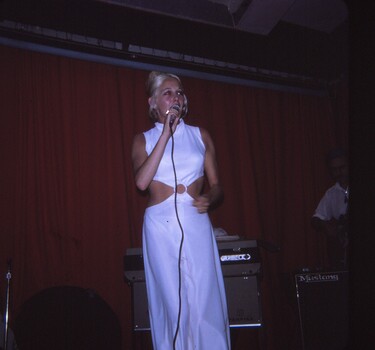 Female entertainer in white dress performing with microphone.